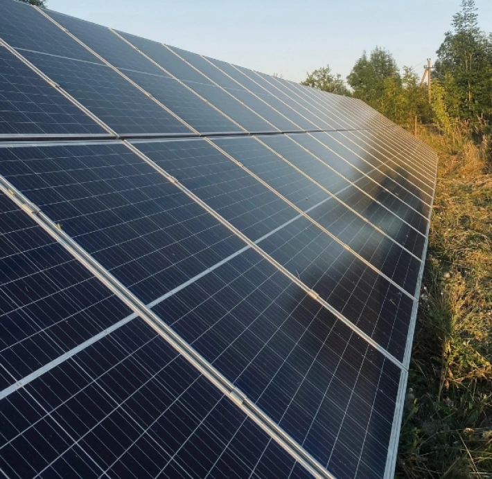 Close-up view of a large ground-mounted solar panel array installed in an open grassy area
